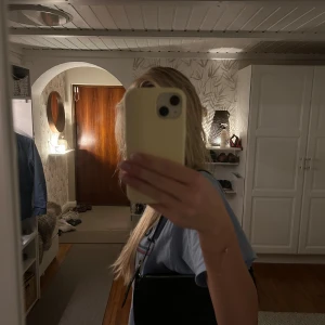 Svart axelväska i croco från Gina Tricot - Snygg svart axelväska från Gina Tricot med croco-mönstrad yta och silverfärgad dragkedja. Väskan har en stilren, rektangulär form och är gjord i syntetmaterial. Perfekt för att lyfta vilken outfit som helst.