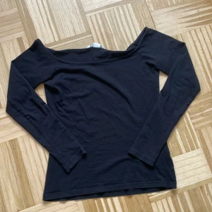 Svart offshoulder topp från H&M - Svart långärmad offshoulder topp från H&M Basic. Snygg och enkel modell med smal passform och bred urringning som sitter snyggt över axlarna. Tillverkad i mjuk bomull som känns skön mot huden. Perfekt att styla med jeans eller kjol.
