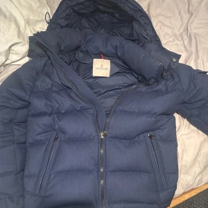 Mörkblå dunjacka från Moncler  - Säljer en snygg mörkblå dunjacka från Moncler. Modellen kallas montgenevre och är väldigt eftertraktad. Jackan har en dragkedja framtill och praktiska fickor med dragkedjor. Den är långärmad och har en luva  för extra värme ! Nypris 22 tusen , mitt pris 7199 men är öppen för byten och förslag, passar storlek m och s men mer small perfekt för dom mellan 179-185