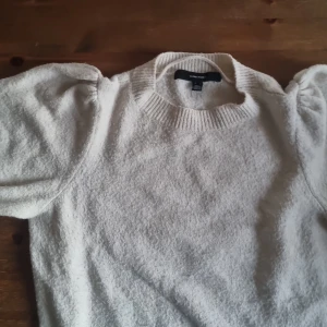 Beige stickad tröja från Vero Moda - Superfin beige stickad tröja från Vero Moda med puffiga axlar och ribbad rund halsringning. Perfekt för dig som gillar en enkel men ändå trendig look. Mjuk och skön, passar till allt och är lätt att styla med dina favoritjeans.