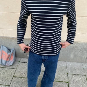 Svartvit randig långärmad tröja - Snygg svart långärmad tröja med vita horisontella ränder. Tröjan har en klassisk, normal passform och är tillverkad i mjukt bomullsmaterial som känns skönt mot huden. Perfekt för dig som gillar stilrena och tidlösa plagg med lite edge.