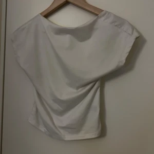 Vit topp med öppen rygg - Säljer en vit topp med korta ärmar och en snygg öppen rygg. 