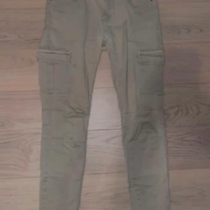 Beiga cargopants från Amisu - Säljer ett par beiga cargopants från Amisu med raka ben och klassiska cargofickor på sidorna. Byxorna har normal passform och är tillverkade i bomull, perfekta för en chill och avslappnad stil.