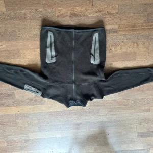 Mörkgrön fleecejacka från Arc'teryx - Mörkgrön fleecejacka från Arc'teryx med hel dragkedja och höga fickor med grå detaljer och dragkedjor. Jackan har lång ärm och en tight passform, perfekt för kyliga dagar. Snygg och funktionell design med diskret logga på ärmen. Fint skick 