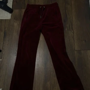 Vinröda manchesterbyxor med snörning - Snygga vinröda manchesterbyxor med raka ben och snörning i midjan. Byxorna har fickor med dragkedja och är perfekta för en chill och trendig look. Mjukt material som känns skönt mot huden.