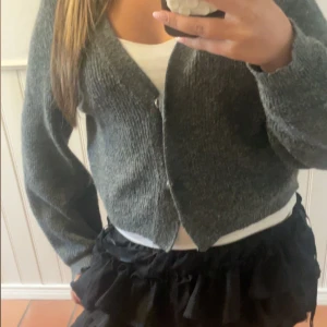 Grå stickad kofta från H&M - Mysig grå stickad kofta från H&M i storlek S. Koftan har v-ringning, knappar framtill och långa ärmar. Perfekt att slänga på sig över en topp för en chill och snygg look. Enkel att matcha med både jeans och kjol. Inga tecken på användning