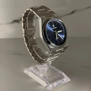 Exklusiv silverfärgad klocka 40 mm - Elegant klocka med en stilren silverfärgad länkarmband och en djupblå urtavla. Klockan har dag- och datumvisning samt en kvartsrörelse. Perfekt för den som söker en tidlös accessoar. BOX, LÄNKJUSTERARE och EXTRA LÄNK medföljer! Priset kan diskuteras.