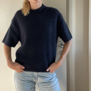 Mörkblå stickad tröja med kort ärm - Säljer en mörkblå stickad tröja med korta ärmar, den är bara använd 1-2 gånger