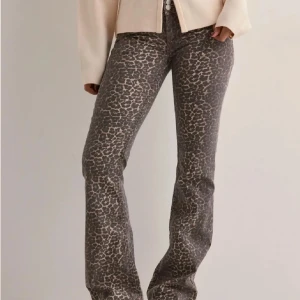 Leopardmönstrade bootcut jeans från Nelly - Snygga bootcut jeans från Nelly med leopardmönster i bruna och beige toner. Byxorna har normal passform och klassisk femficksdesign. Perfekta för dig som vill sticka ut med ett djurmönster och ändå ha en bekväm jeanslook.