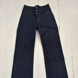 Acne 2021m raw denim  - Acne 2021m raw denim.raka, vida ben. Nypris 5000kr Klassisk femficksmodell med knäppning fram och tydliga kontrastsömmar. Tillverkade i 100% bomull för en autentisk jeanskänsla. Perfekta för dig som gillar stilrena och trendiga byxor.