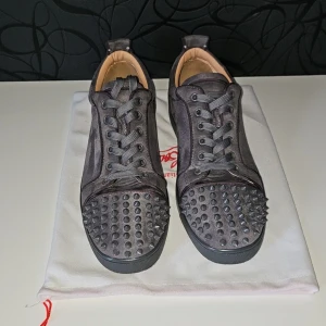 Christian Louboutin - Gråa sneakers från Christian Louboutin i mocka med ikoniska röda sulor och coola gråa taggar vid tårna. Skorna har snörning och rund tå, samt lyxig läderinsida. Har tyvär ingen låda bara dustbag. 