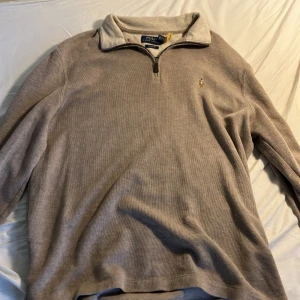 Beige half zip tröja från Polo Ralph Lauren - Säljer en beige långärmad tröja från Polo Ralph Lauren med klassisk broderad logga på bröstet. Tröjan har en stilren krage och half zip-dragkedja. Materialet är mjukt och ribbat, perfekt för lager-på-lager under höst och vinter. Längd på modellen: 180. Storlek S. Nypris 2300 kr.