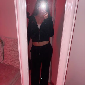 Svarta Juicy couture tracksuit   - Svarta mjukisbyxor(s) och hoodie(xs)  från Juicy Couture i mjuk sammet med strassdetaljer och broderad logga. Byxorna har snörning i midjan och breda muddar. Klassisk Juicy-stil med glittrande text baktill, perfekta för en chill och trendig look. 