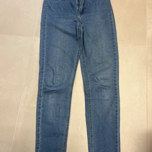 Blå skinny jeans med hög midja - Snygga blå skinny jeans med hög midja finns fläckar på fram och baksida. Jeansen har en smal passform hela vägen ner. Perfekta för dig som gillar en tight och stilren look.