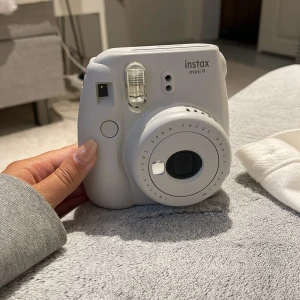 Instax Mini 9 - Fujifilm Instax Mini 9 i vitt/grå blå. Kameran är i gott skick med några mindre repor och märken på baksidan, men fungerar utmärkt. Perfekt för att ta direktbilder och få dem utskrivna direkt. Enkel att använda och populär för fester och resor.