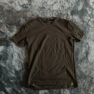 Svart t-shirt från Calvin Klein - En stilren svart t-shirt från Calvin Klein med diskret ck-logo nere vid fållen. Klassisk rund halsringning och korta ärmar. Tillverkad i mjuk bomull som känns skön mot huden. Perfekt för en clean och enkel look.