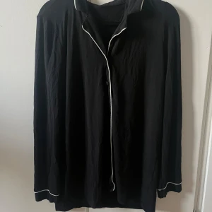 Svart pyjamas skjorta från Intimissimi storlek S - Svart långärmad pyjamas skjorta från Intimissimi med vita kontrastsömmar längs krage, knappslå och ärmslut. 