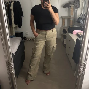 Beiga manchester cargopants - Säljer ett par beiga cargopants i mjuk manchester med stora fickor på sidorna och relaxed fit. Byxorna har elastisk midja med knapp och klassiska cargodetaljer. 