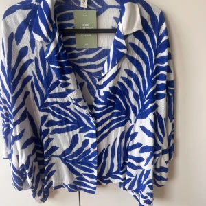 Blåvit zebramönstrad skjorta H&M - Säljer en blåvit skjorta från H&M med zebramönster. Skjortan har krage, knappar framtill och är tillverkad i 100% LENZING ECOVERO viskos. Perfekt för dig som vill sticka ut med ett coolt mönster och skön passform.