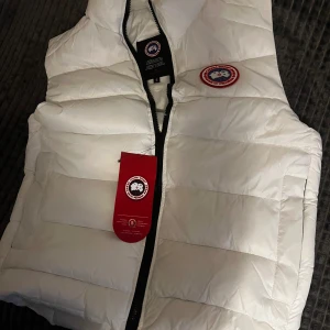 väst från Canada Goose - Säljer en snygg vit dunväst från Canada Goose 