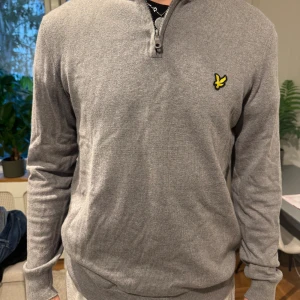 Grå half zip tröja från Lyle & Scott - Grå långärmad tröja från Lyle & Scott. Tröjan har half zip i halsen och är tillverkad i mjuk bomull. Perfekt för lager-på-lager och enkel att matcha med jeans eller chinos. Kan gå ner i pris vid snabb affär!