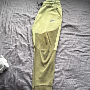 Gröna mjukisbyxor från Nike  /spodnie od nike - Snygga gröna mjukisbyxor från Nike med elastisk midja och dragsko. Byxorna har ribbade muddar vid bensluten, fickor med dragkedja och en broderad Nike-logga på låret. Perfekta för chill eller träning, tillverkade i mjukt material.