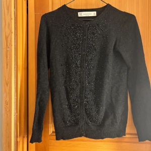 Svart kofta med pärlor från ZARA - Mysig svart kofta från ZARA med pärldetaljer framtill. Koftan har rund hals, knäppning hela vägen och är långärmad. Materialmix med bomull, viskos, nylon, angora och kashmir för extra mjuk känsla.