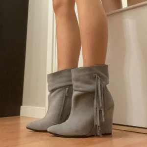 As snygga kilklack boots, isabel marant liknande, fringe boots  - Storlek 38. Grå boots i mocka med med tråd detalj. Har en liknande design som isabel marant. Dem är jättefina men kommer tyvärr inte till användning. Fringe boots. En aning liten i storleken så en person med storlek 37 borde också kunna använda dem. 