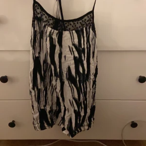 Zebramönstrad linnetopp från ONLY - Säljer en svartvit linnetopp från ONLY i storlek 34. Toppen har zebramönster, tunna axelband och en snygg spetsdetalj upptill. Perfekt för dig som gillar djurmönster och vill ha en lätt och luftig topp till sommaren.