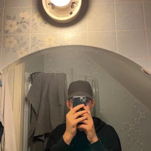 Gucci keps med GG-mönster - Säljer en svart Gucci keps med klassiskt GG-mönster och den ikoniska gröna och röda randen på sidan. Kepsen har böjd skärm och justerbar rem bak. Perfekt för dig som vill ha en stilren och lyxig accessoar.