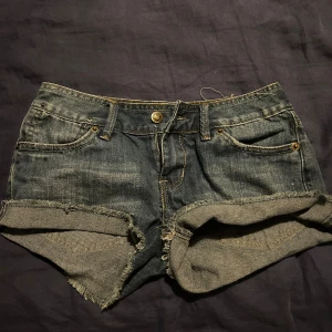 Mörkblå jeansshorts från Old Navy - Snygga mörkblå jeansshorts från Old Navy med lite högre midja och råa, fransiga benslut. Klassisk femficksmodell med uppvikta kanter och slitna detaljer för en avslappnad vibe. Perfekta för varma dagar och enkel att matcha med allt. Pris kan diskuteras 