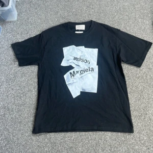 Maison Margiela svart t-shirt - Svart t-shirt från Maison Margiela med ett stort grafiskt tryck i vitt och svart på bröstet. Storlek M. Skick 9/10