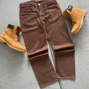 Bruna raka jeansbyxor - Snygga bruna jeansbyxor med rak passform och klassisk femficksdesign. Byxorna har normal midja och är tillverkade i bomullstyg. Perfekta för dig som gillar en enkel och stilren look. Midja 41 cm, lårvidd 31 cm, innerben 20 cm, total längd 102 cm.