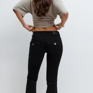 Svarta bootcut jeans från Gina Tricot - Snygga svarta lågmidjad jeans från Gina Tricot med bootcut passform. Jeansen har silverfärgade knappar och detaljer. Pris kan diskuteras.💕