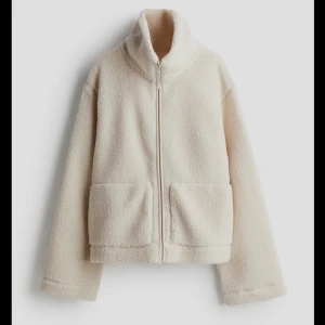 Brun teddyjacka med dragkedja - Mysig teddyjacka i färgen BRUN (hittade inte bilden) med hög krage och två stora fickor framtill. Jackan har en rak passform och stängs med dragkedja. Perfekt för kyliga dagar när du vill vara både varm och stilren.