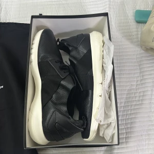 Svarta sneakers Hypnotic Yellow x Lynk & Co - Snygga svarta sneakers i skinn och textil från Hypnotic Yellow för Lynk & Co. Skorna har en chunky vit sula med XL Extralight-teknologi, elastiska band över ovandelen och coola detaljer i läder och textil. Perfekta för dig som gillar stilrena och moderna sneakers.