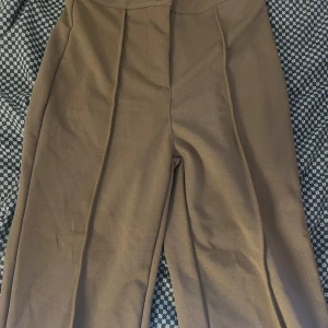 Bruna kostymbyxor från Shein XS - Snygga bruna kostymbyxor från Shein i storlek XS. Byxorna har hög midja, raka ben och pressveck framtill för en clean look. Materialet känns mjukt och har en lätt stretch. Perfekta att styla med sneakers eller boots.