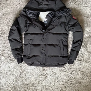 Canada Goose jacka - Exklusiv Canada Goose Macmillan Parka i svart – en ikonisk vinterjacka med stilren design och oöverträffad värme. Perfekt balans mellan lyx, funktion och komfort för kalla dagar.  ♦️ Storlek S – normal passform ⚜️ Helt nytt skick med tagg ♦️ Premium dunfyllning för maximal värme  📦 Fraktas inom 24 timmar & trygg affär 