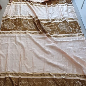 Gardin - Säljer en stor vanlig gardin i beige och brunt med vackert blommönster. Gardinens kanter har en fin fransdetalj som ger en extra touch av stil. Längd: 248 cm och Bredd: 141cm. (Det är en gardin men vet inte vilken slags men den är inte så tunn)