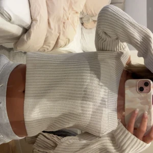 Offshoulder ribbad stickad tröja vit - Säljer en vit offshoulder stickad tröja med ribbad struktur. Tröjan har lång ärm och är croppad i modellen.