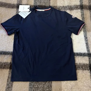 Moncler Maglia T-Shirt Navy - Säljer en mörkblå Moncler Maglia T-shirt, den är nyskick aldrig använd. Storlek M, vid intresse eller frågor är det bara höra av dig. Originallappar medföljer vid köp, priset kan diskuteras inom snabbaffär eller bundleköp Mvh✅