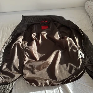 Quiltad brun jacka från Zara Man - Säljer en mörk grön jacka från Zara skön att ha på sig. Med snyggt rutmönster och dragkedja framtill. Jackan har en stilren ståkrage, två fickor och är helfodrad. Perfekt för dig som gillar en clean look med lite edge.