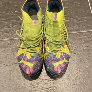 Puma Future Ultimate FG AG storlek 42,5 - Säljer ett par  Puma Future Ultimate FG AG i storlek 42,5. Skorna har en färgstark design i grönt, gult, blått och rosa med grafiska mönster och Pumas logga på ovansidan. Stickad ovandel med snörning och platt sula för bästa grepp på planen. Nypris är ca 2000 kr.  Priset är inte spikat så går att diskutera. Som ni ser på bild 5 så är dom lite slitna. De går att limma ihop, och de är dom ända defekterna på skorna