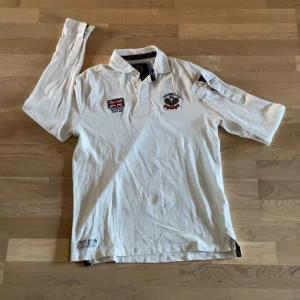 Vit pikétröja Morris Tennis Club - Vit långärmad pikétröja från Morris med broderade detaljer. Taggen visar S men passar M