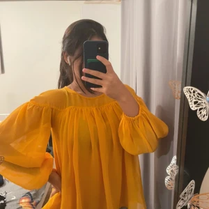 Indiska-orange Off-Shoulder Blouse - Size 34 - Nytt utan tag • Storlek: EU 34 • Klarorange färg • Off-shoulder-modell med resår i halsringningen • Böljande, lätt tyg • Puffiga ballongärmar för en snygg look • Perfekt för sommaren, fester eller avslappnade chica outfits Aldrig använd, bara provad. Kommer från ett rökfritt och djurfritt hem.