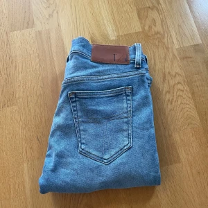 Ljusblå jeans från Tiger of sweden - Snygga ljusblå jeans från Tiger of sweden med klassisk femficksdesign och brunt läderpatch bak i midjan. Modellen är slim. Jeansen är tillverkade i mjukt denimtyg med lätt tvättad look och har knapp och dragkedja framtill.