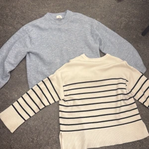 Två stickade tröjor, blå & randig - Säljer två stickade tröjor: en ljusblå med rund hals och en beige med svarta ränder och bred ribbad mudd. Båda har lång ärm och är perfekta för lager-på-lager-stil. Sköna och stilrena basplagg för garderoben. (Säljer båda tillsammans för 150kr)