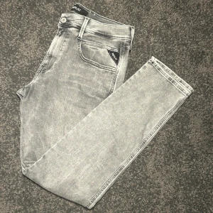 Replay Hyperflex Anbass grå jeans - Pris kan diskuteras. Säljer ett par Replay Hyperflex Anbass jeans i grå tvätt med snygga raka ben och klassiska fem fickor. Stretchigt material för extra komfort och cool Replay-logga på fickan. Passar dig som gillar stilrena och moderna jeans med smal passform.