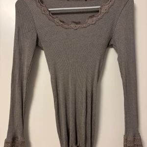 Beige ribbad långärmad topp med spets från Twilfit  - Beige ribbad långärmad topp med snygga spetsdetaljer vid halsringningen och ärmsluten. Har tyvärr klippt bort lappen med varifrån den är men om jag minns rätt var det Twilfit💕