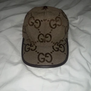Brun keps med gg mönster på den - Säljer en snygg keps i beige och brunt med det klassiska GG-mönstret över hela kepsen. 